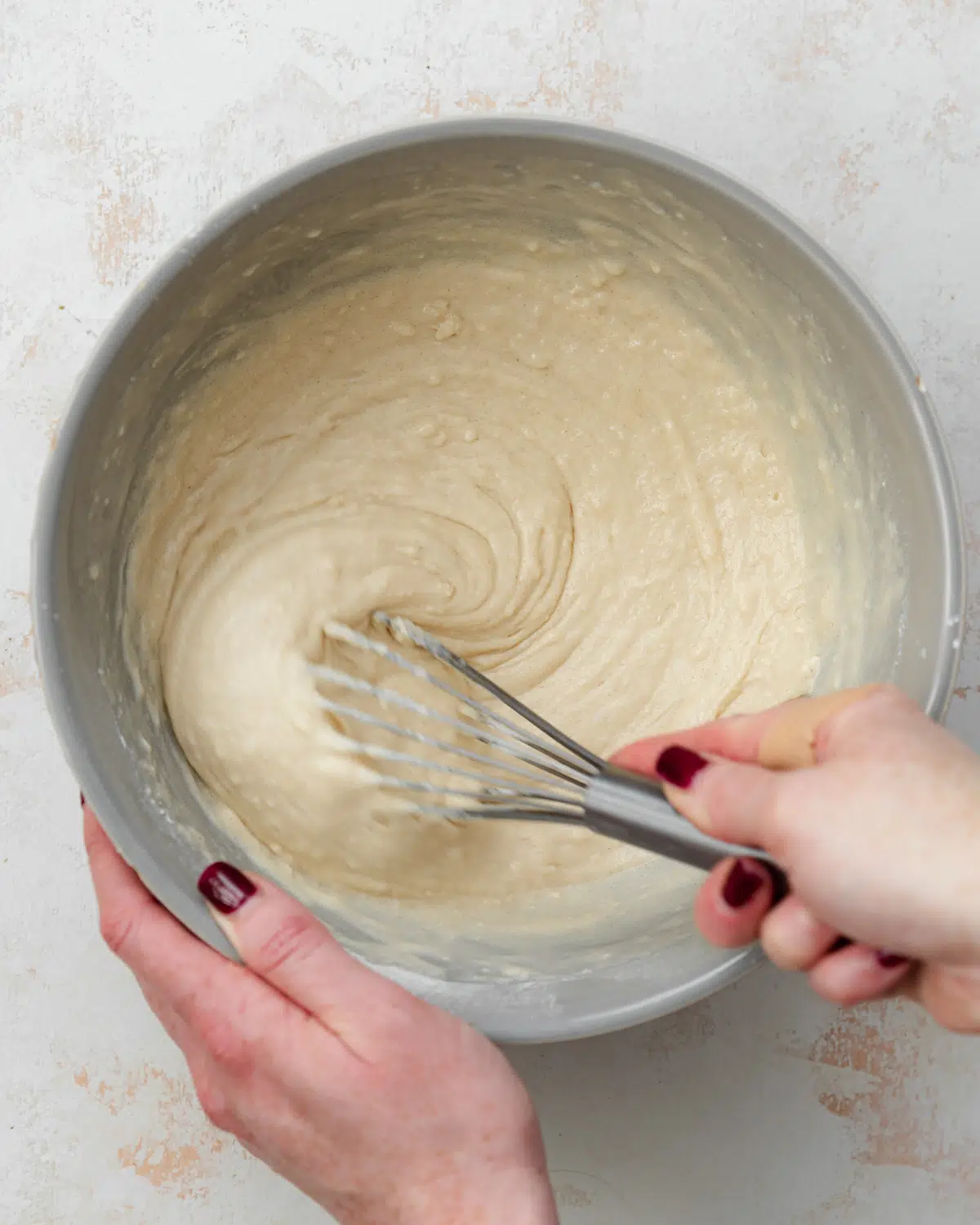 whisking vanilla cupcake batter in a bowl.
