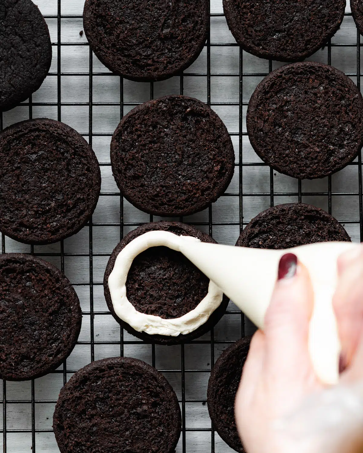 piping cream filling into oreo cookies.