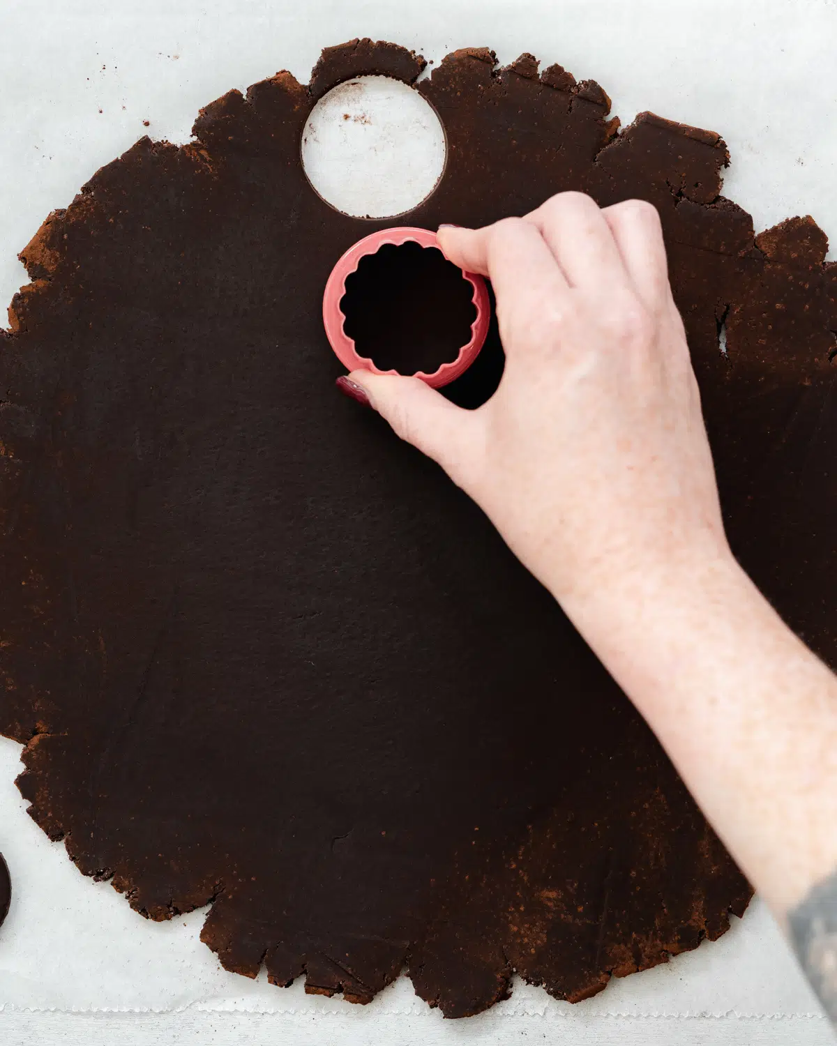 cutting circles out of oreo cookie dough with a cookie cutter.