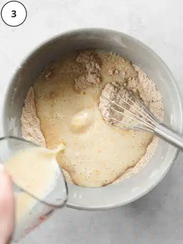 pouring wet ingredients into large bowl of flour to make vegan carrot cake.