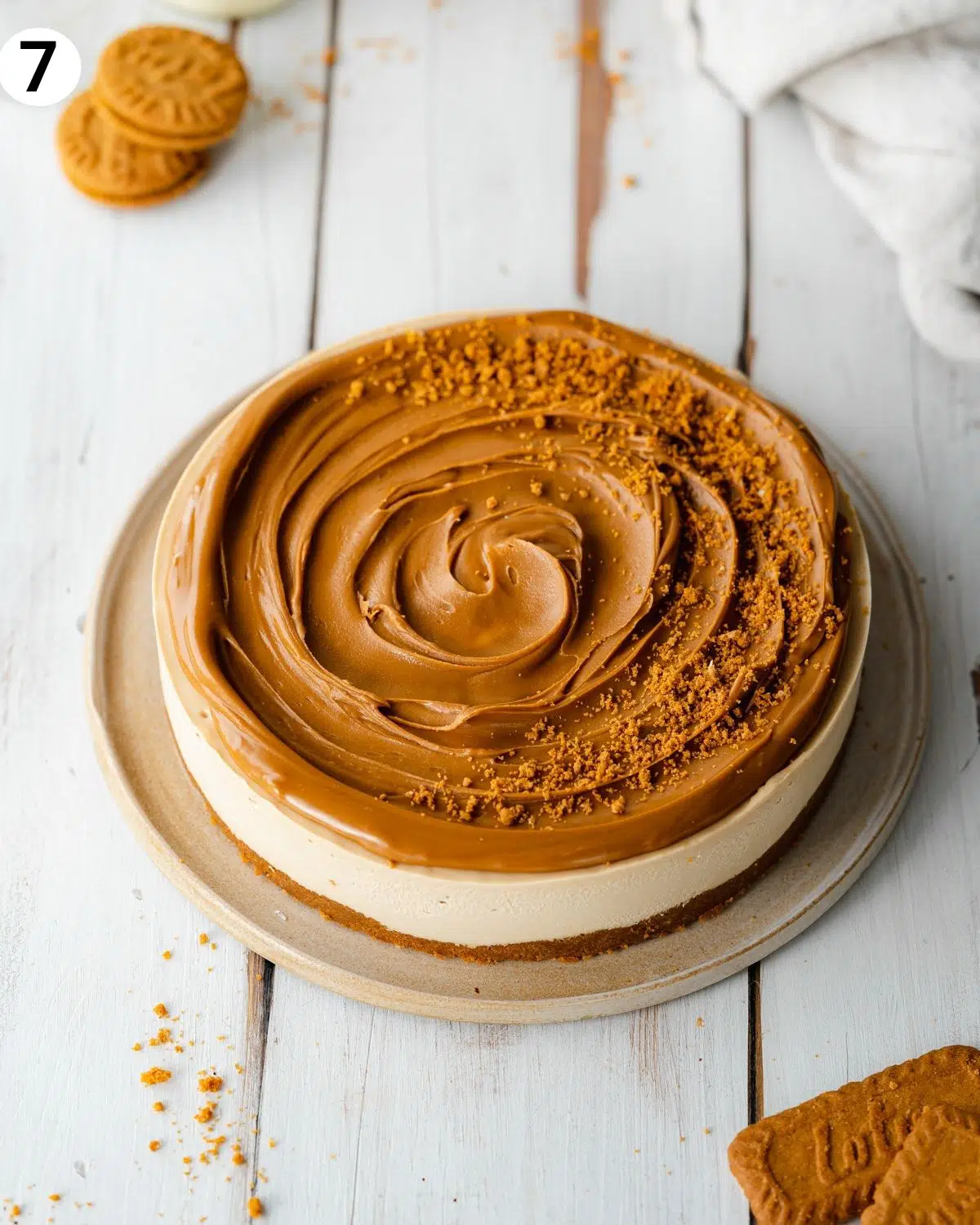 vegan biscoff cheesecake on a white wooden surface.