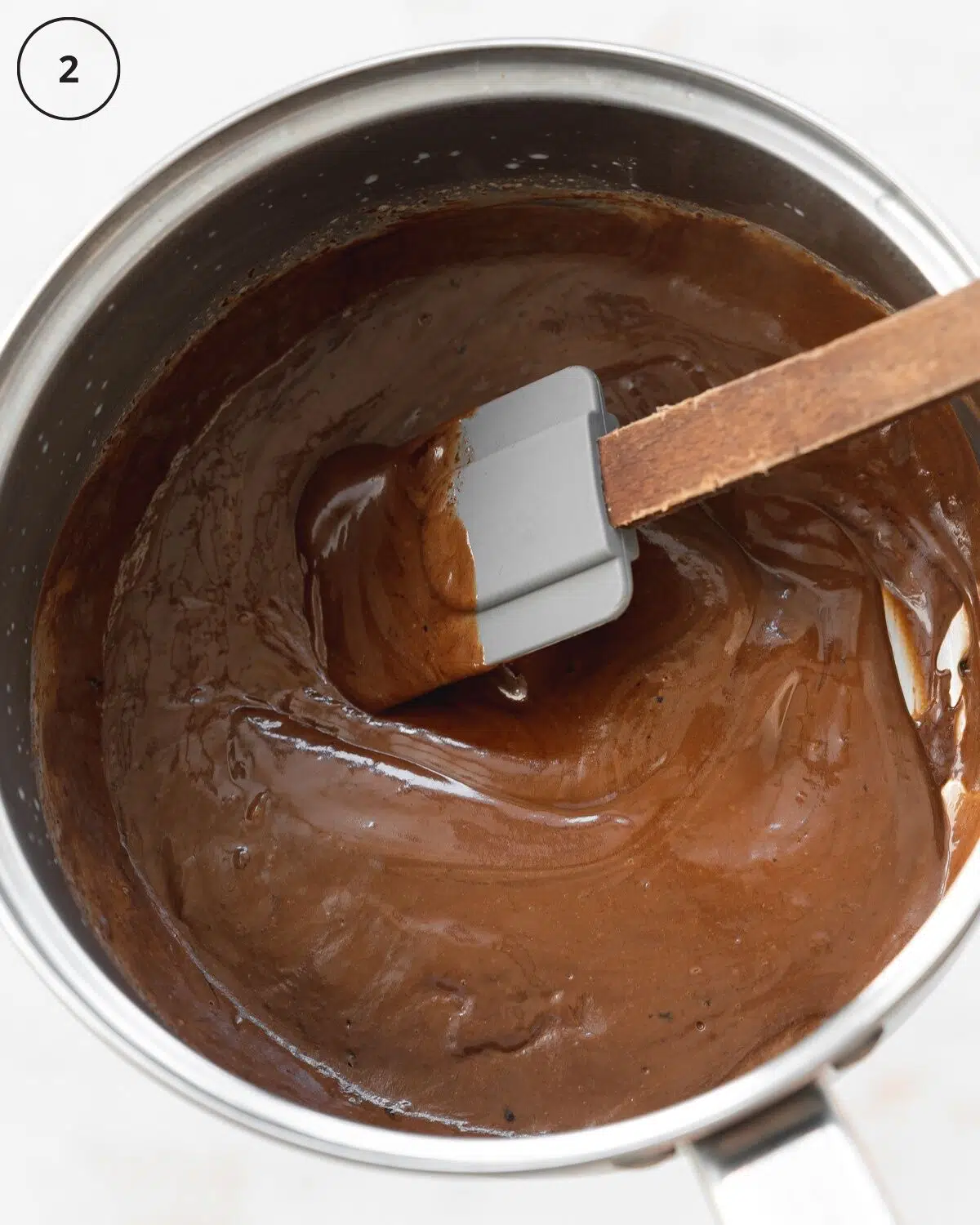 chocolate ganache in a saucepan with a spatula inside.