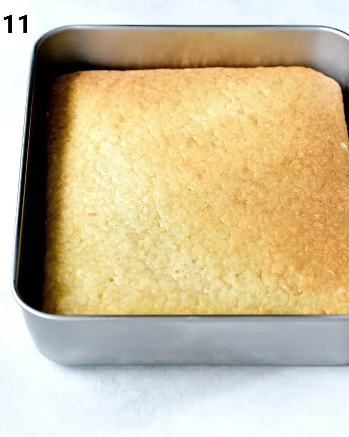 side view of tres leches cake in a metal square baking tin.
