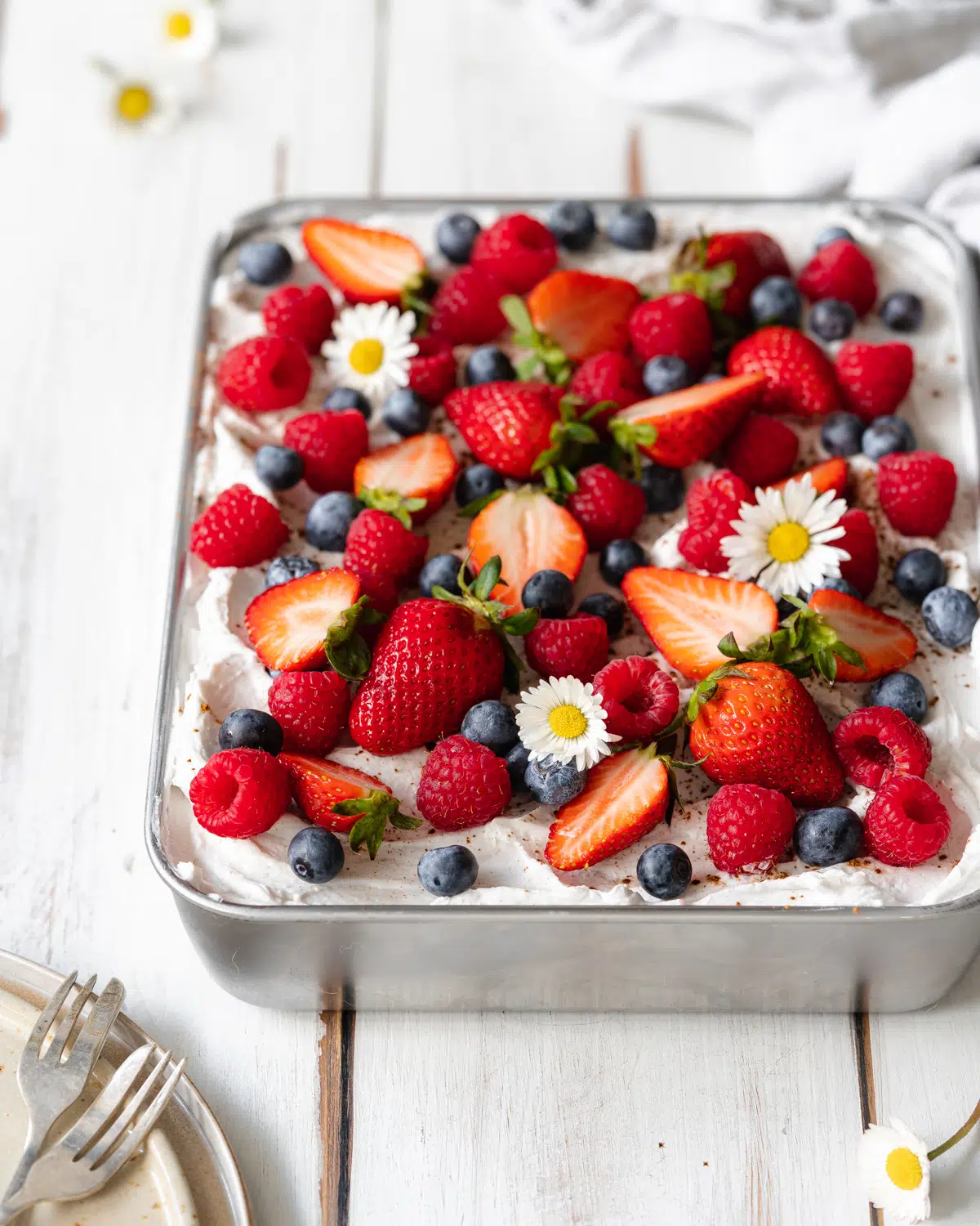 tray of tres leche with fresh strawberries, blueberries and raspberries on top.