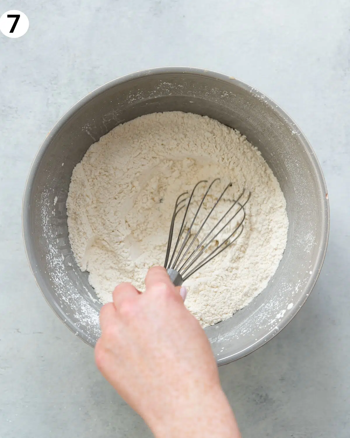 whisking flour in a grey bowl.