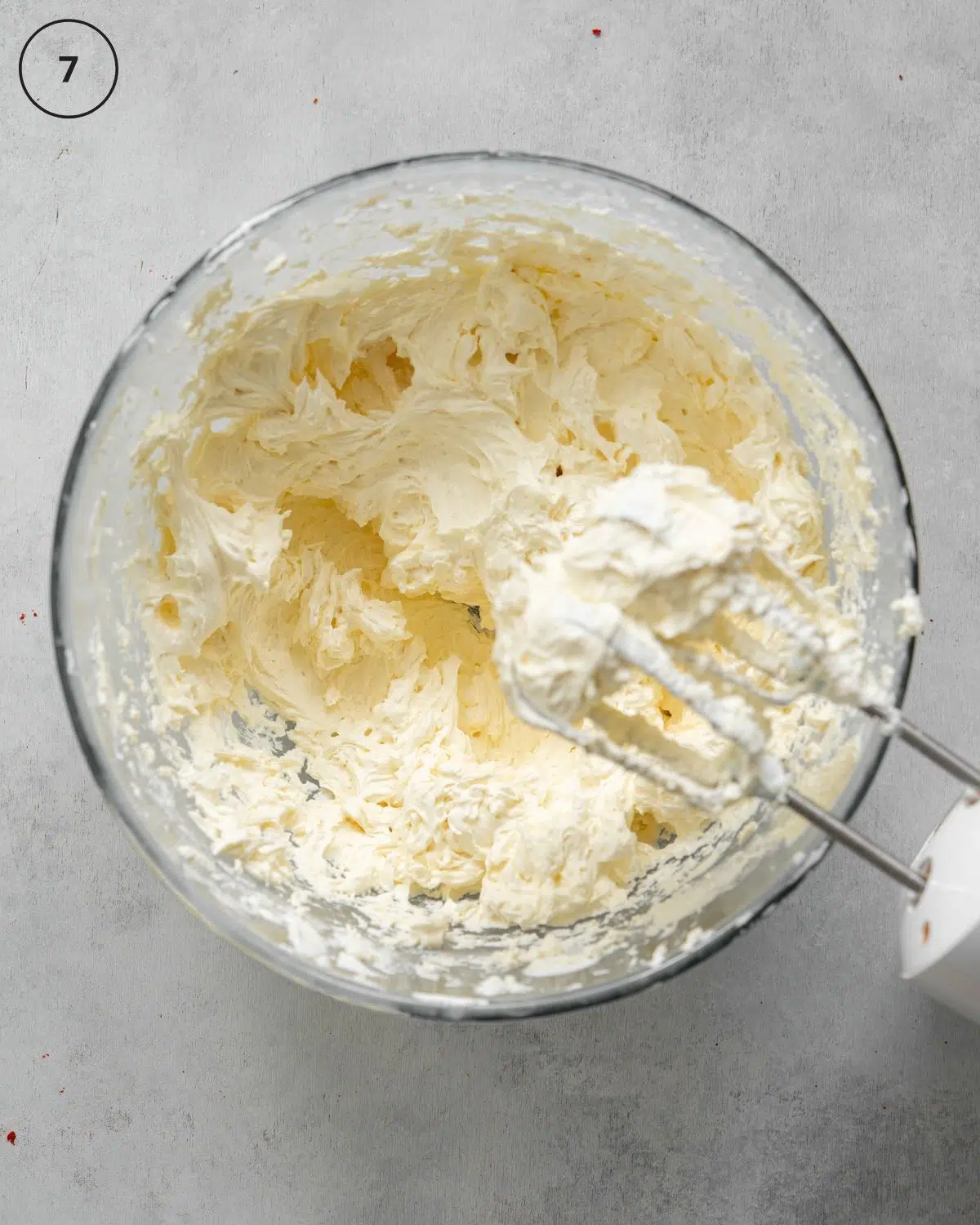 whisking buttercream in a clear bowl.