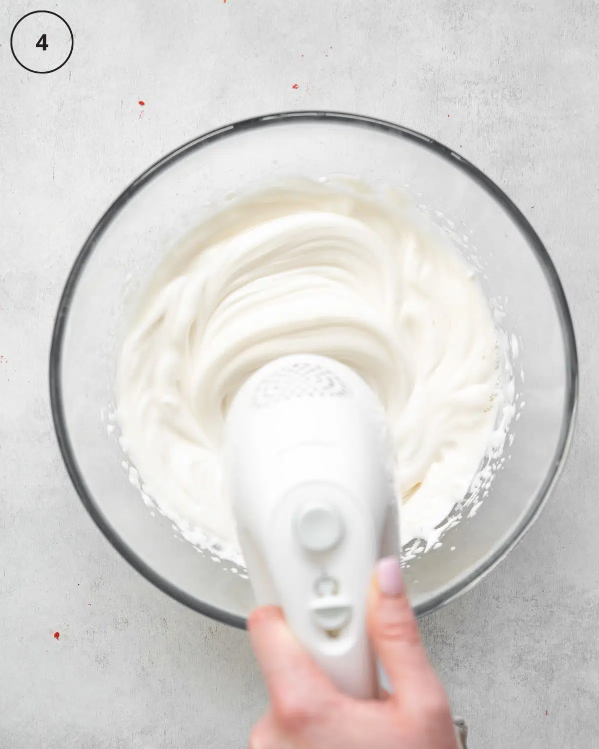 top down view of hand whisking aquafaba meringue with electric mixer.