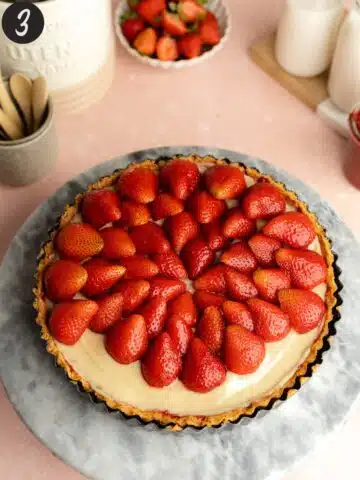 arranging strawberries on top of a pastry cream-filled shortcrust pastry tart.