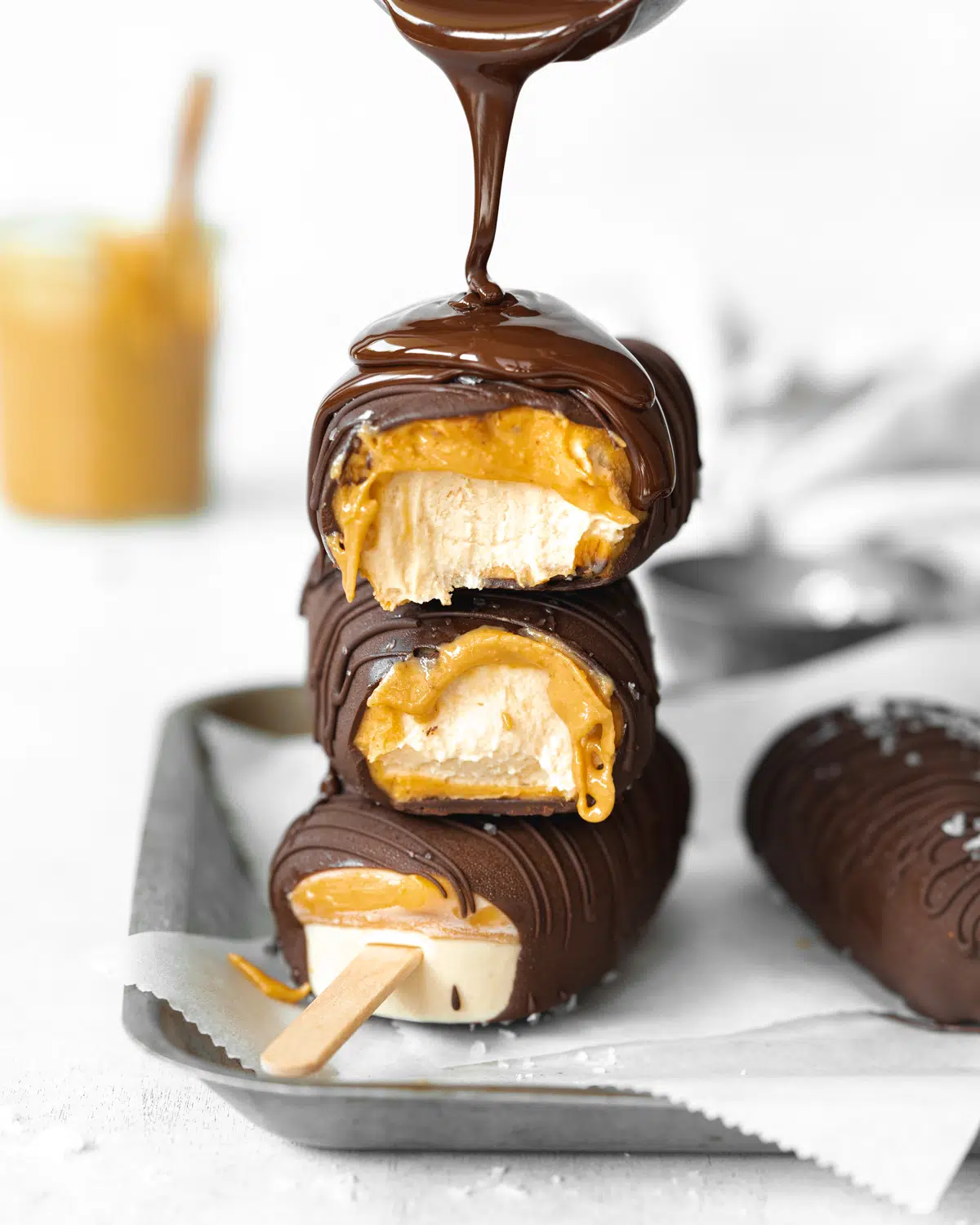 stack of magnum ice cream bars with peanut butter with chocolate being poured over them.
