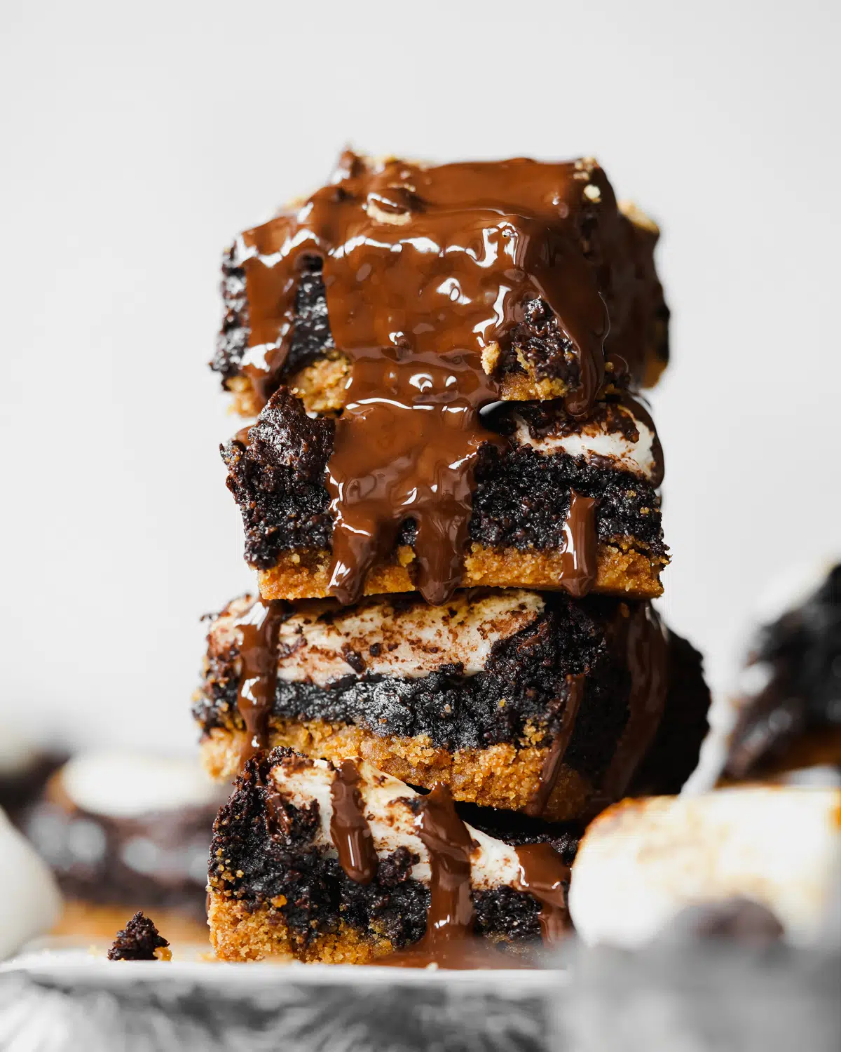 stack of s'mores brownies with chocolate sauce dripping down the sides.
