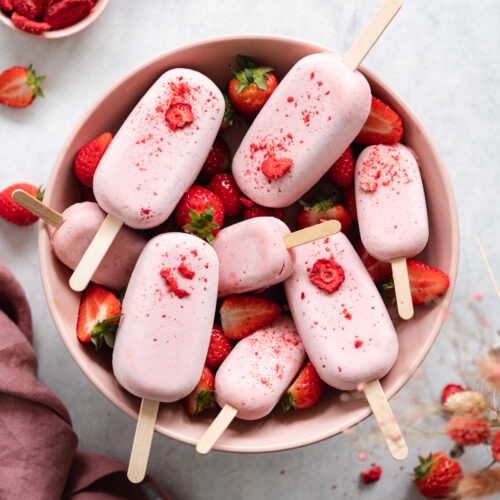 strawberry ice cream bars in a pink bowl with fresh strawberries.