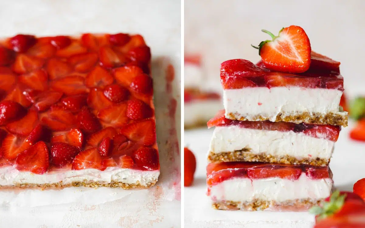strawberry and vanilla cheesecake slices stacked on top of each other with fresh strawberries scattered around them.