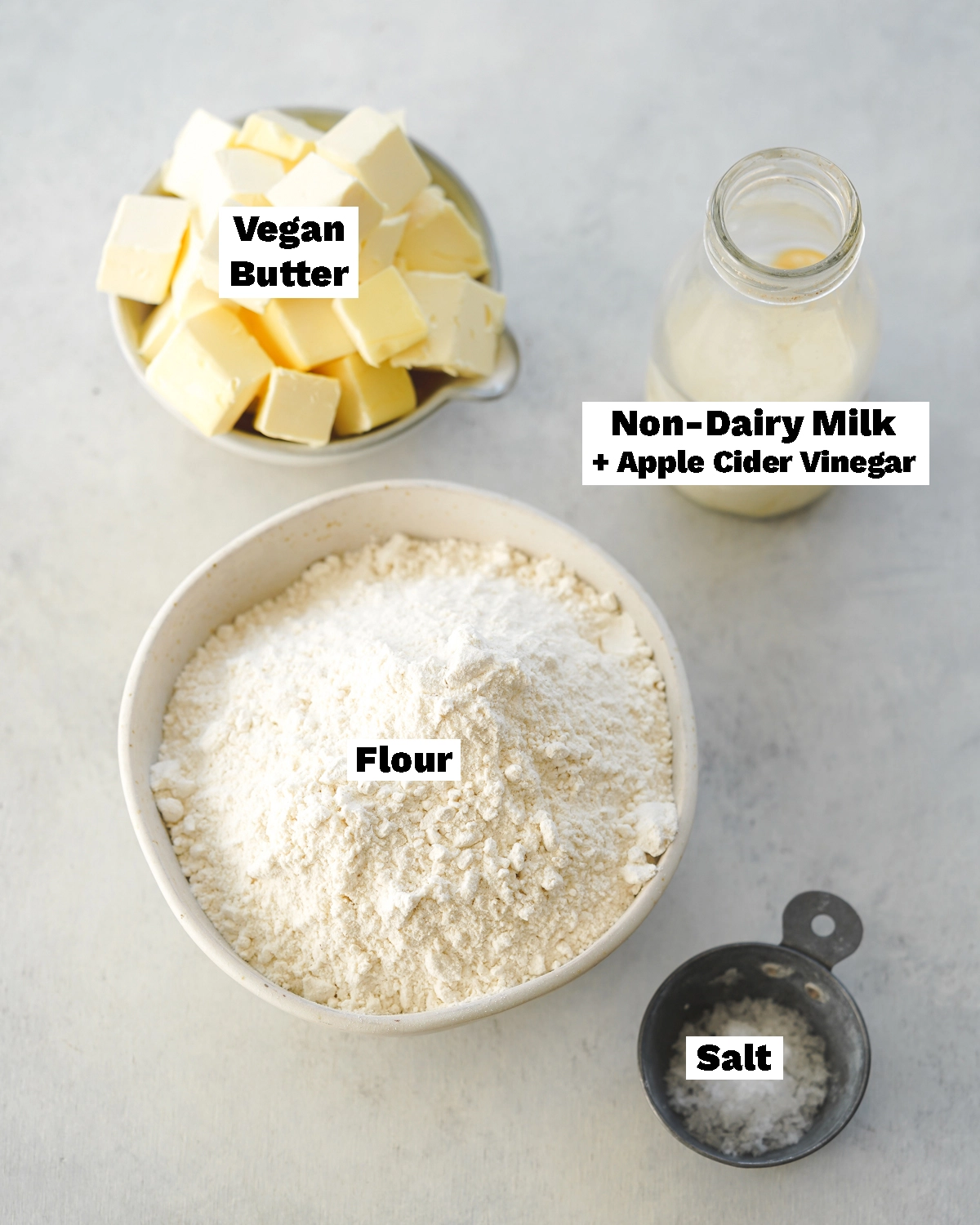 ingredients to make vegan pie crust measured out in bowls on a grey surface.
