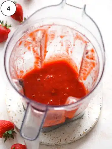 freshly made strawberry coulis in a blender jug showing the smooth consistency and bright red color.