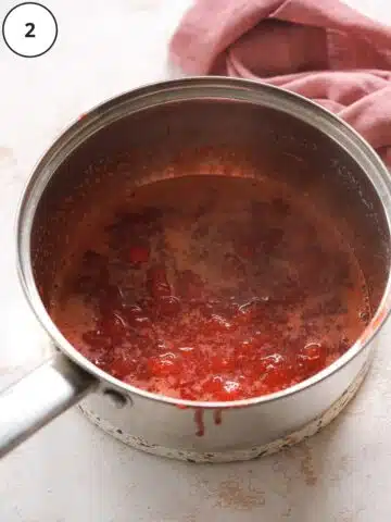 strawberries, sugar, and lime juice cooked down into a jam in a saucepan.