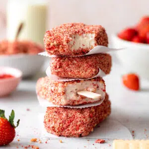 stack of strawberry shortcake ice cream bars with strawberries and shortbread cookies scattered around.