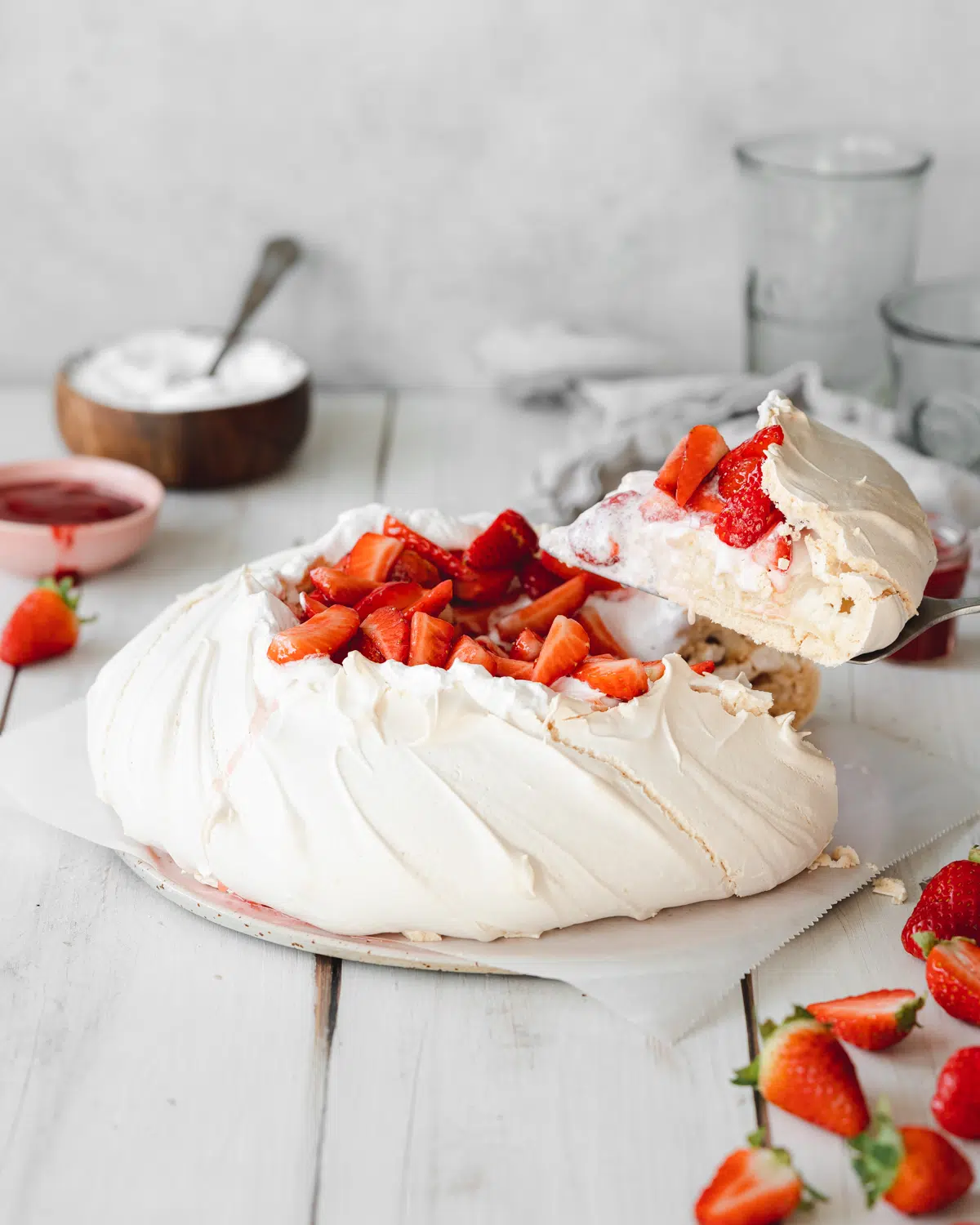pavlova with strawberries on top and scattered around it.
