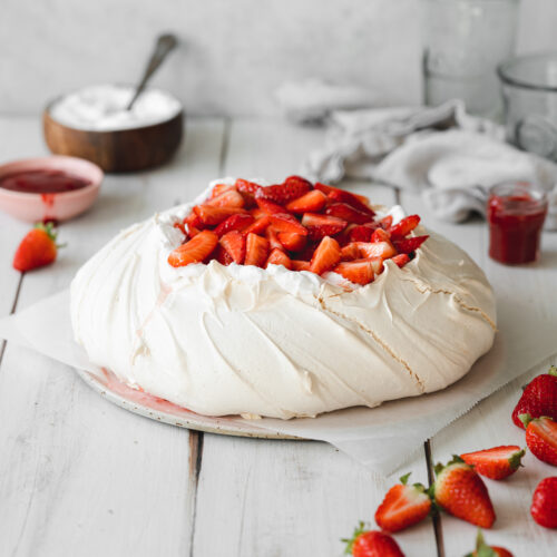 vegan pavlova on a ceramic plate with coconut cream and strawberries.
