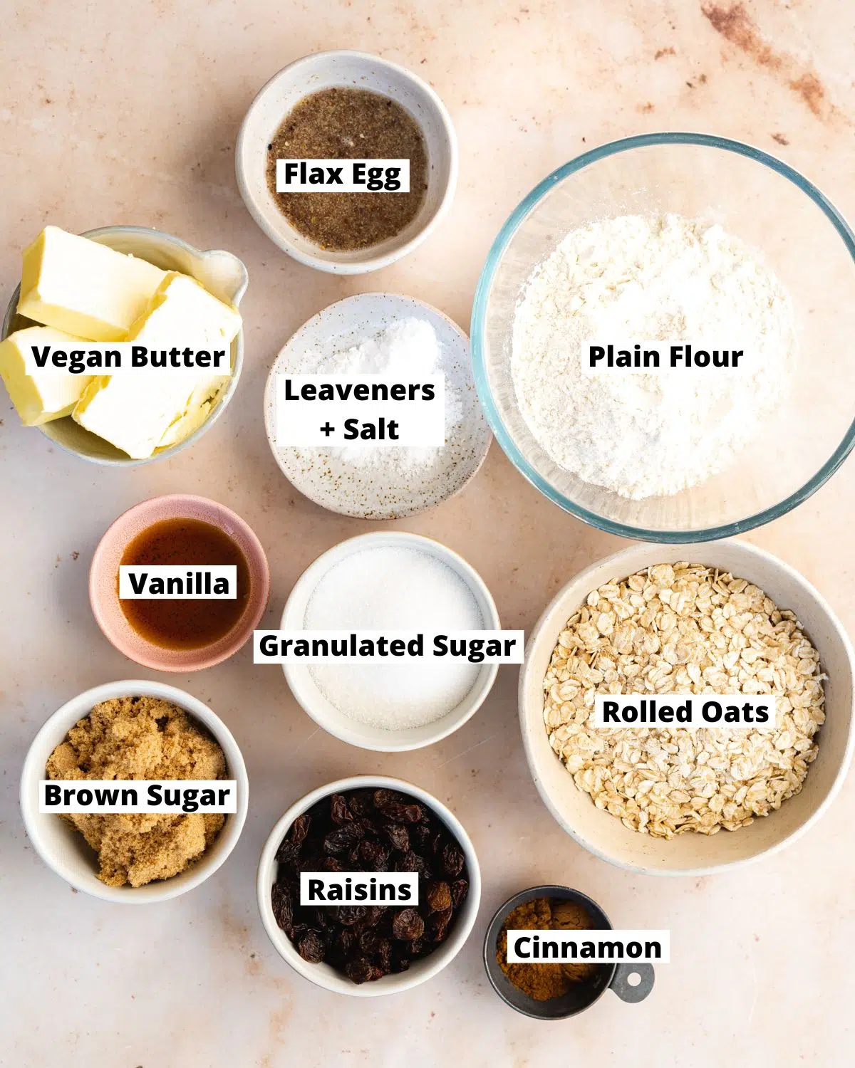 ingredients to make vegan oatmeal raisin cookies measured out in bowls.