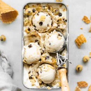 chocolate chip cookie dough ice cream in a metal loaf pan with crushed ice cream cones around it.