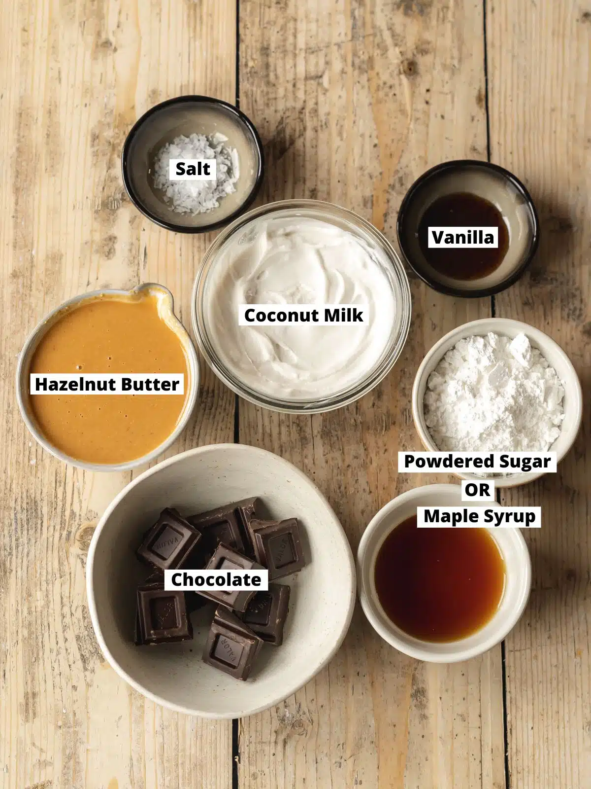 Ingredients needed to make vegan Nutella chocolate hazelnut spread measured out into bowls on a wooden table.