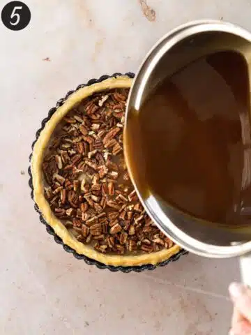 pouring caramel sauce into a pie crust with chopped pecans before going into the oven to bake.