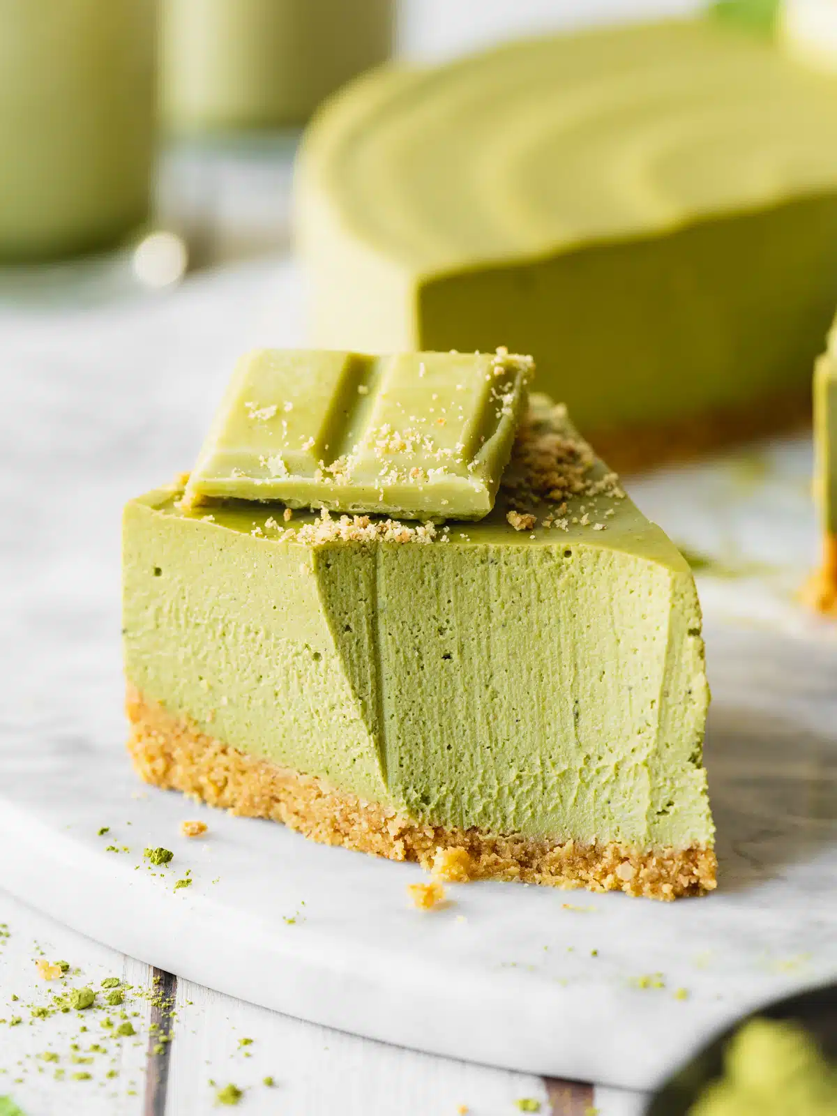 slice of matcha cheesecake with a spoon taken from it on a marble surface.
