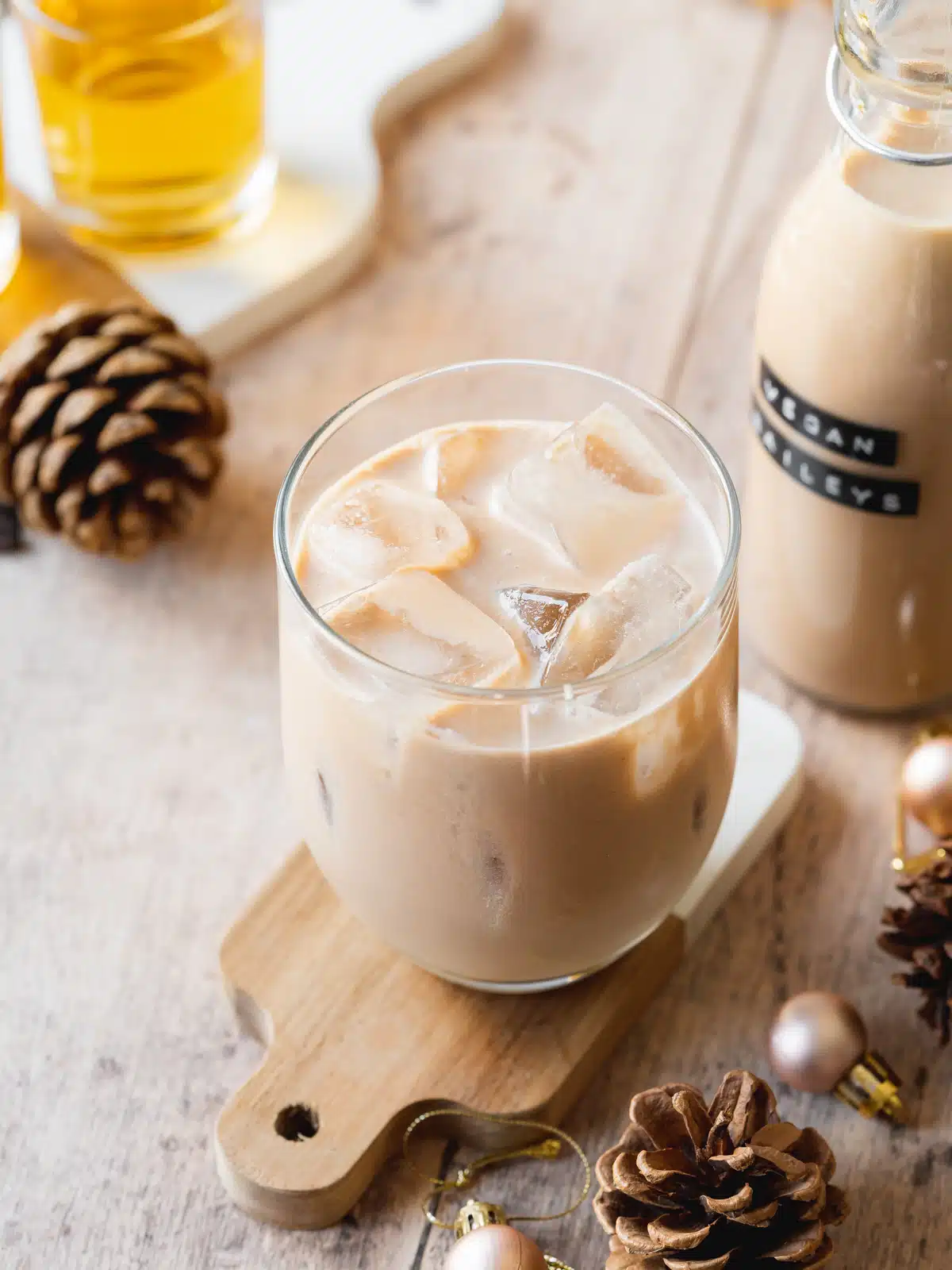 a glass of homemade baileys with ice on a small wooden board.