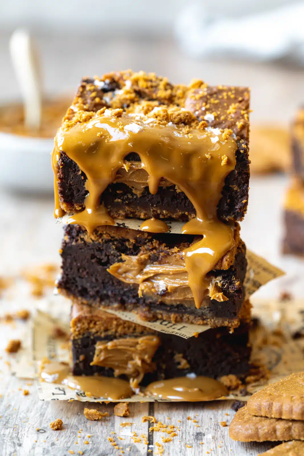 stack of biscoff brownies with cookie butter drizzled on top and lotus biscuits scattered around them.