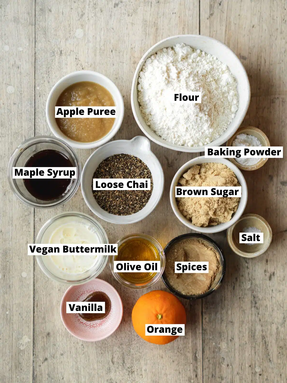 ingredients for chai bread measured out in bowls on a wooden surface.
