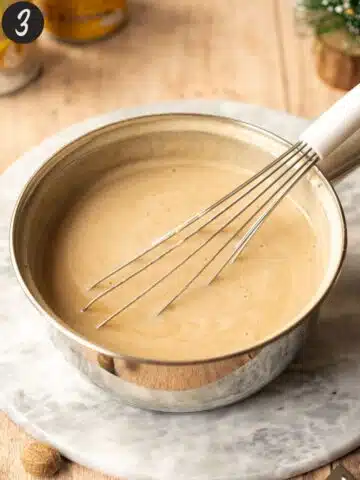 freshly made oat nog in a saucepan with a whisk.