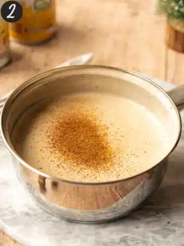 vegan eggnog in a saucepan with freshly grated nutmeg on top.