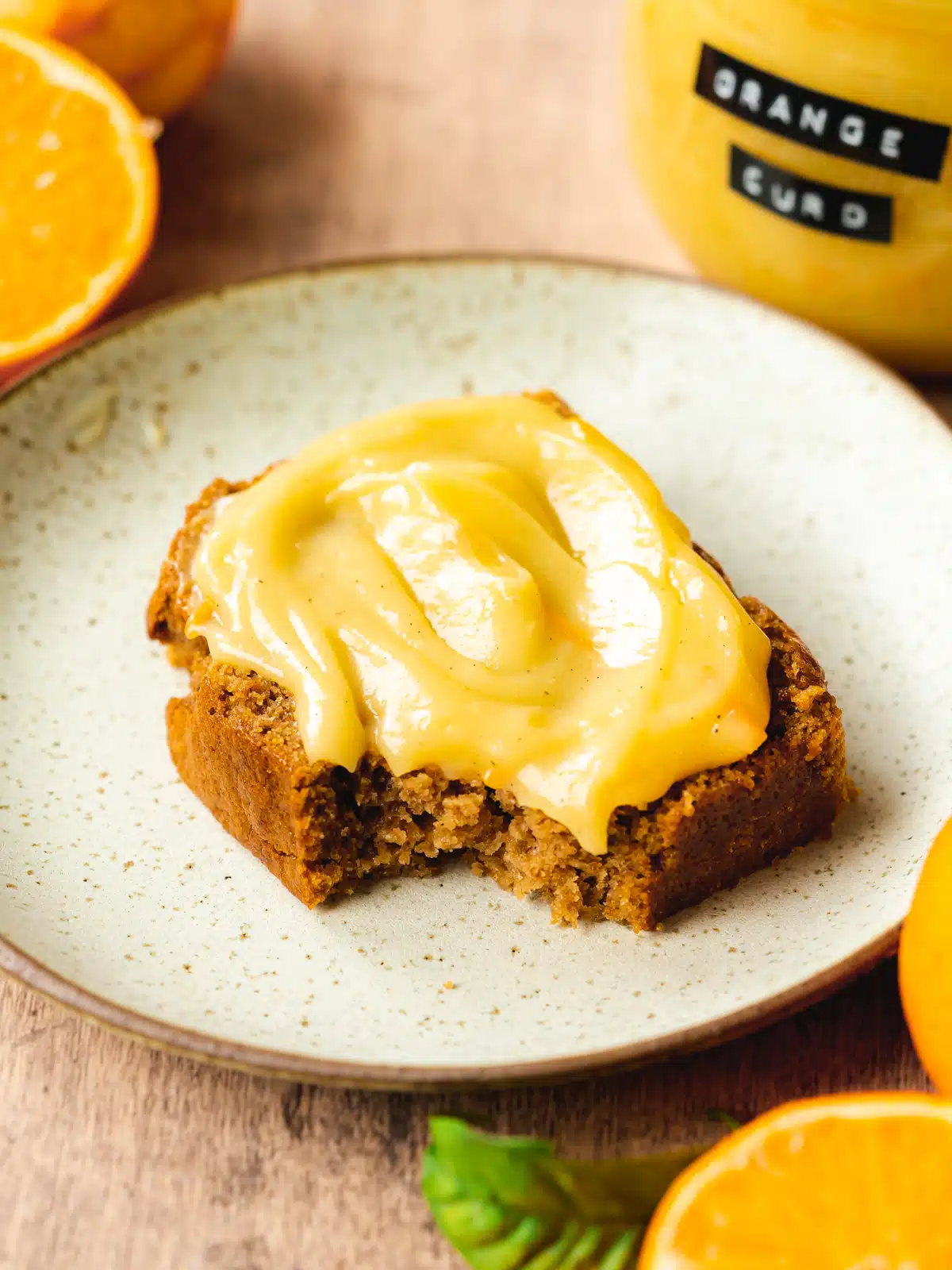 a slice of sweet bread with a thick layer of orange curd and a bite taken from it.