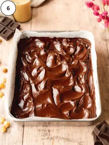 raw brownies in a rectangular baking tin with swirled ganache topping.
