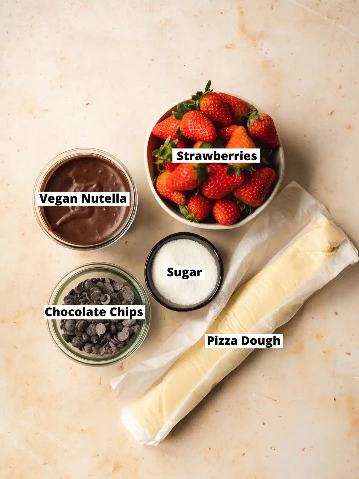 ingredients to make chocolate pizza measured out in bowls on a marble surface.