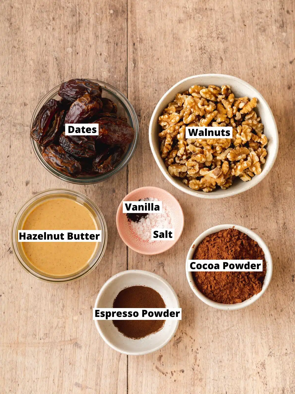 ingredients for no bake brownies measured out in bowls on a wooden surface.