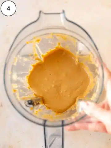 Homemade creamy roasted peanut butter in the blender jar after continuing to blend for several more minutes.