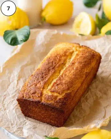 Vegan lemon loaf after baking on a piece of crumpled parchment. The center has a nice, deep crack, perfect for filling with glaze.