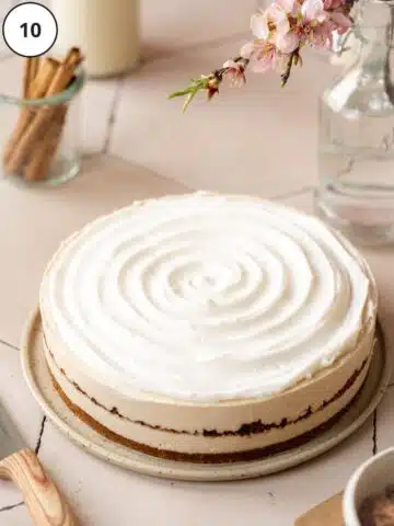 Cream cheese icing added to the vegan cinnamon roll cheesecake in a swirly top layer after freezing and removing the outer springform sleeve.