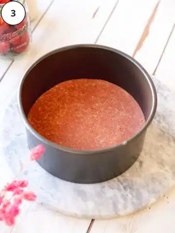 pink strawberry cheesecake crust pressed down into a cake pan.