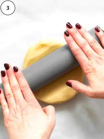 two hands rolling out sweet pastry with a rolling pin.
