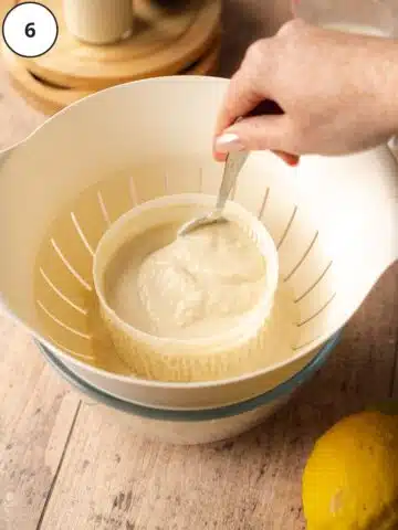 cashew ricotta cheese being stirred in a cheese making mold on top of a colander.
