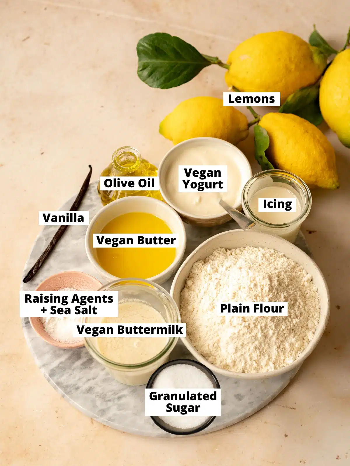 ingredients needed to make vegan lemon loaf measured out into bowls on a pink table.