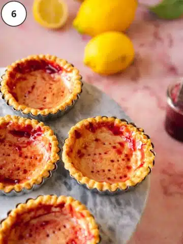 Baked vegan tart shells are brushed with raspberry jam.