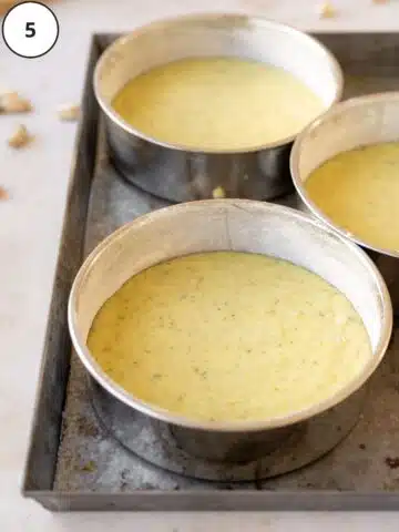vegan pistachio cake batter in lined cake tins ready to go into the oven.