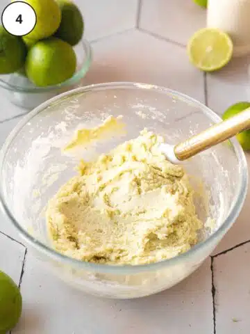 Vegan key lime cookie dough in a mixing bowl after folding in the dry ingredients with a spatula.