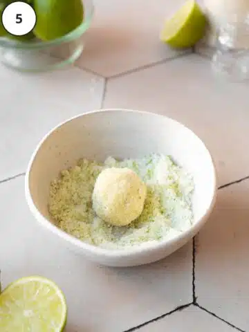 Rolling a lime cookie dough ball in the reserved lime sugar mixture.