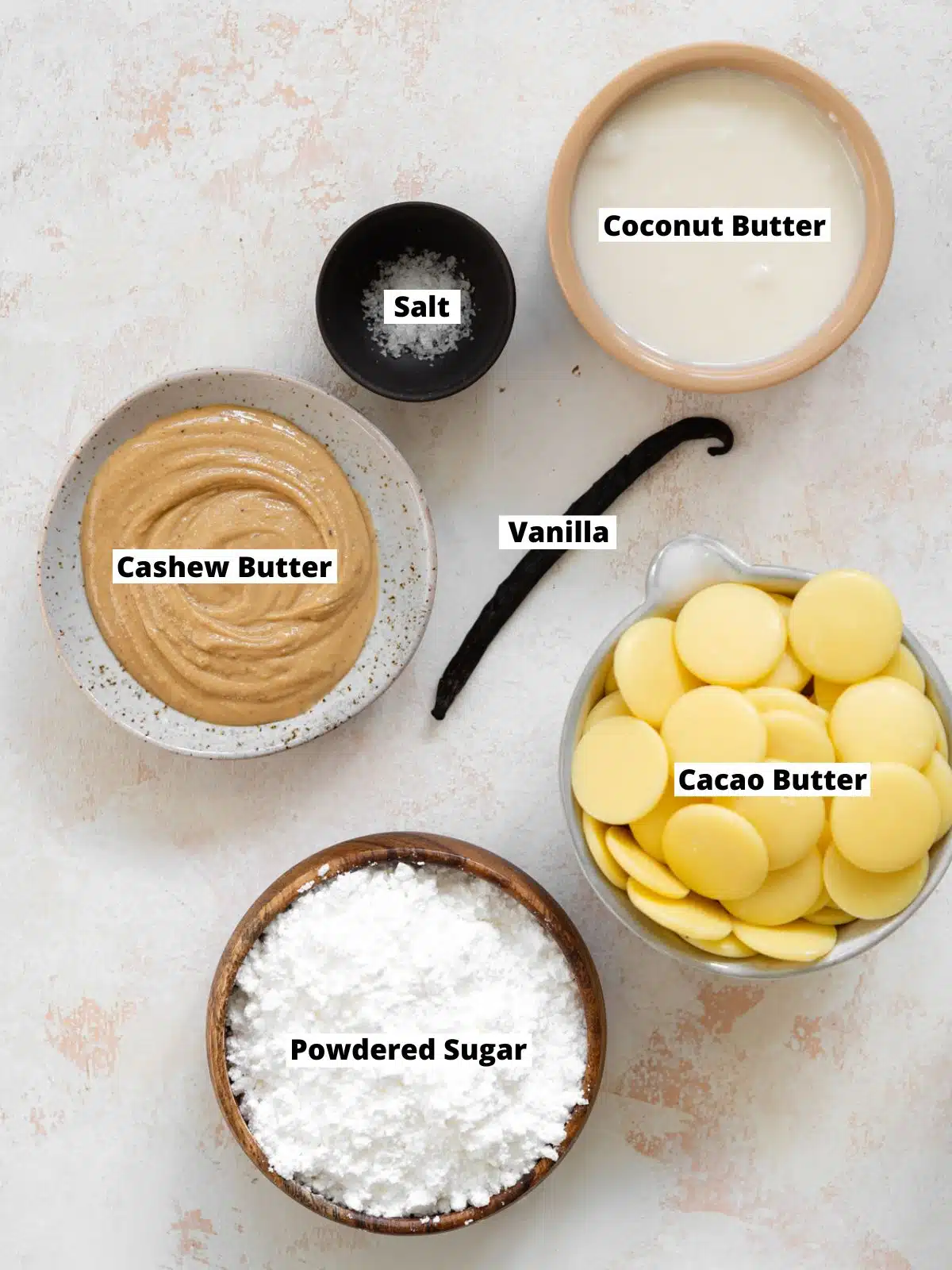 ingredients to make dairy free white chocolate bars measured out in bowls on a white surface.