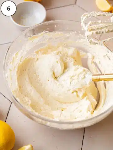 vegan lemon buttercream in a large clear mixing bowl with a spatula showing the thick consistency.