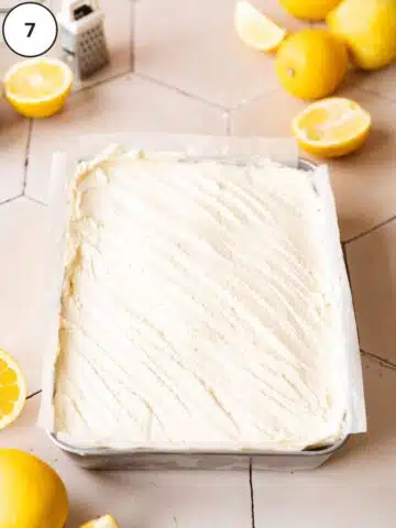 a lemon sheet cake with a thin layer of lemon frosting in a metal baking pan.